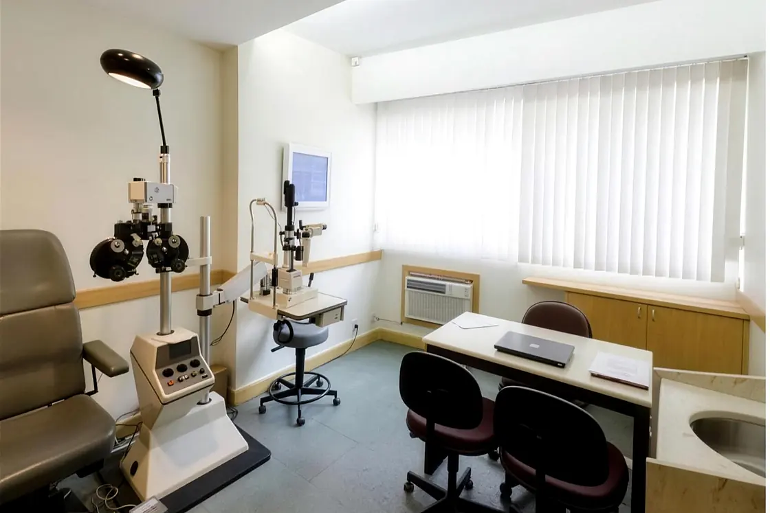 Consultório de oftalmologia da Benchimol, com o refrator, a cadeira de exame e a mesa do médico