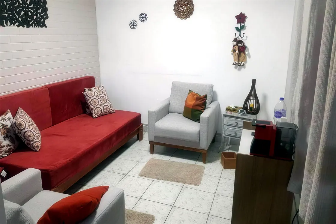 Sala de atendimento da Ciclos, com sofá vermelho, poltronas e almofadas