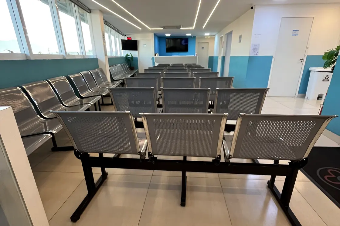 Sala de espera da unidade KM 32, com as fileiras de cadeiras e as janelas ao fundo
