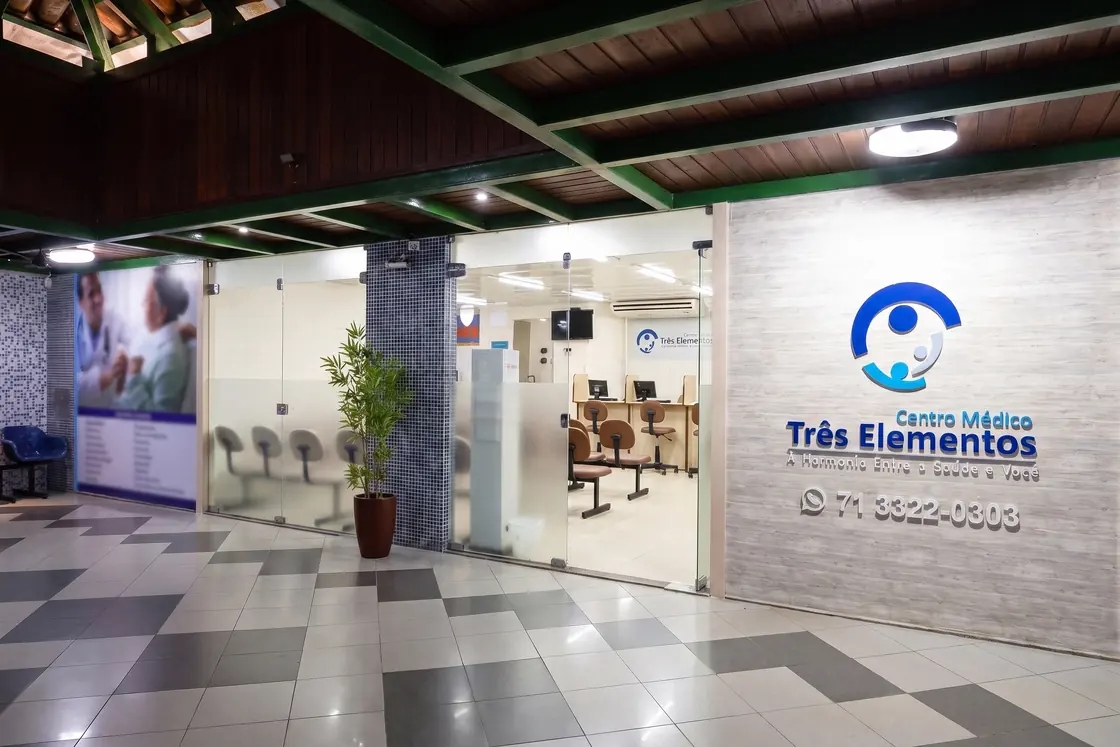 Entrada do Centro Médico Três Elementos, com a marca na parede ao lado das portas de vidro