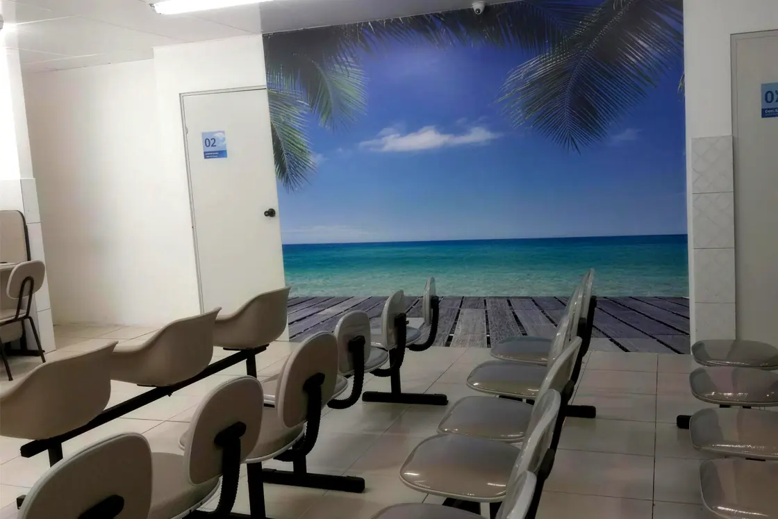 Sala de espera do Centro Médico Três Elementos, com o painel de praia na parede