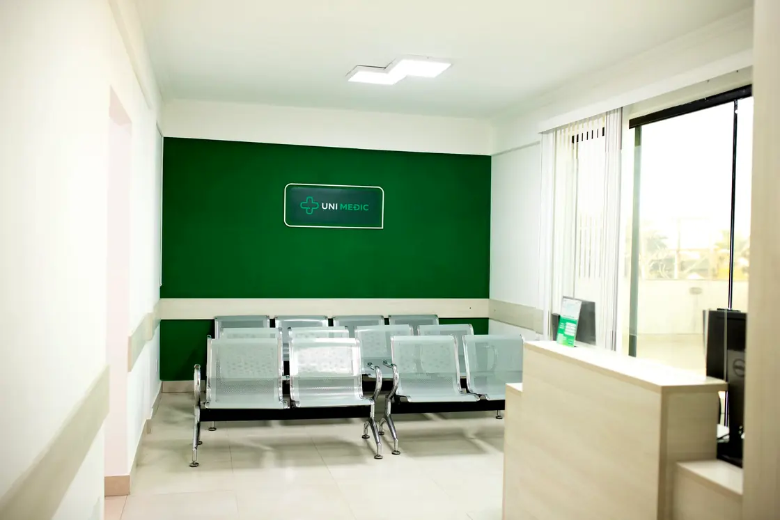 Recepção da Unimedic, com a parede verde, a marca e as cadeiras de espera